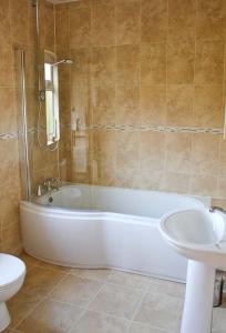 a bathroom with a tub and a toilet and a sink at Moat Farm Cottage in Wood Dalling