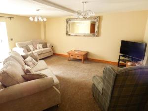 a living room with a couch and a tv at Corner Croft in Earl Sterndale