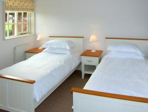 two beds in a bedroom with two lamps on tables at Dairy Apartment 2 in Knutsford