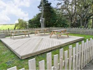 twee picknickbanken op een houten platform in een hek bij No 2 Low Hall Cottages in Scalby