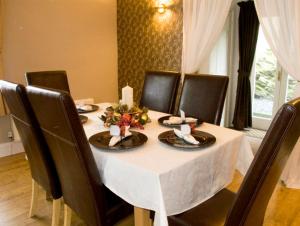 a dining table with black chairs and a white table cloth at Briarcliffe Cottage in Lindale +4 photos