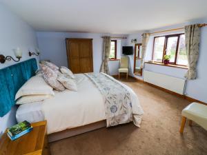 a bedroom with a bed and a desk and windows at Hazelwood Cottage in Ingleton