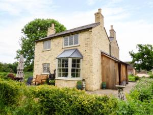 een oud bakstenen huis met een patio ervoor bij Shortmead Cottage in Biggleswade