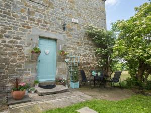 una casa de piedra con una puerta azul y una mesa en West Wing Cottage, en Sandhoe