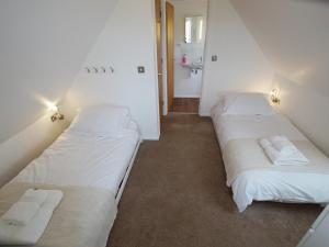 two beds in a room with white sheets and towels at Beautiful Cotswold View in Bourton on the Water