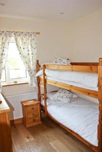 2 Etagenbetten in einem Zimmer mit Fenster in der Unterkunft Moat Farm Cottage in Wood Dalling
