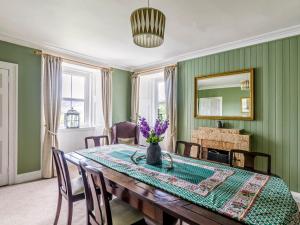 a dining room with a table with purple flowers on it at Rottal Farmhouse in Millton of Clova