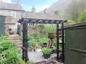 a garden with a wooden pergola in front of a house at 73 Ravensdale Cottages in Millers Dale