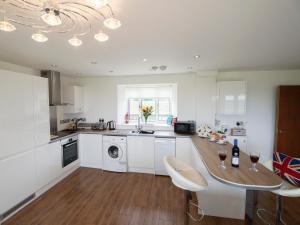 a kitchen with white cabinets and a table with wine glasses on it at Beautiful Cotswold View in Bourton on the Water