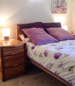 una cama con almohadas moradas junto a una mesita de noche en 73 Ravensdale Cottages, en Millers Dale