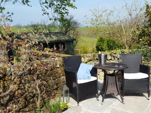 un patio con mesa, sillas y pared de piedra. en Bridleway Cottage, en Wennington