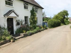 a white house with flowers on the side of a road at George Cottage in Clun