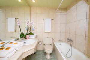 a bathroom with a toilet, sink and tub at Creta Hotel in Agios Nikolaos