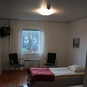 um quarto com uma cama, 2 cadeiras e uma janela em Rågårdsvik em Grundsund