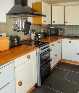 a kitchen with white cabinets and a stove top oven at Y Lleiaf in Holyhead