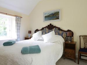 a bedroom with a white bed with a blue towel on it at Bannatyne Lodge in Newtyle