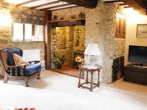 a living room with a fireplace and a chair and a television at 7 Gretton in Cardington