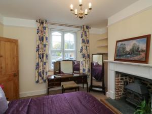 a bedroom with a bed and a desk and a fireplace at 3 Old Police Station in Dunster