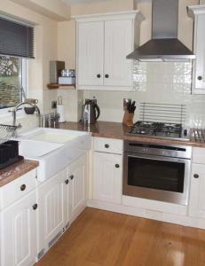 a kitchen with white cabinets and a sink and a stove at Hour Cottage in Stow on the Wold