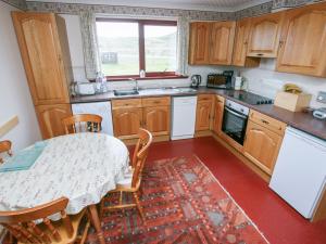 a kitchen with a table and a table and chairs at 2 Bayview Bungalow in Poolewe