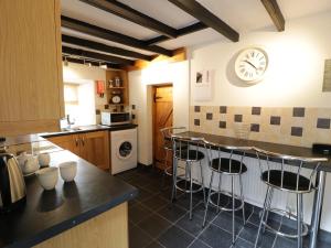 a kitchen with bar stools and a clock on the wall at Ty Cynon in Blaenau-Ffestiniog