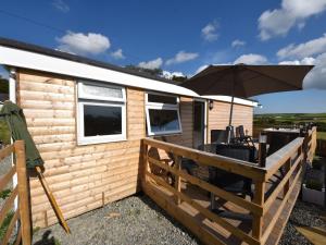 a cabin with a deck and an umbrella at Y Caban Clyd in Morfa Nefyn