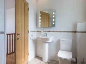 Un baño con lavabo, inodoro y espejo. en Boscarne, en St Ives