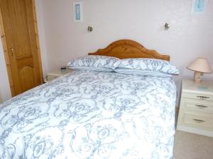 a bed with a blue and white comforter and pillows at 1 Bayview Bungalow in Poolewe