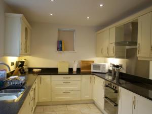 a kitchen with white cabinets and black counter tops at Margaret House in Pooley Bridge