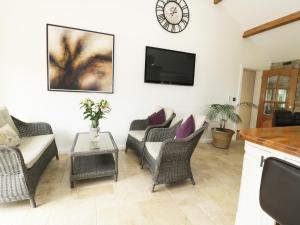 uma sala de estar com cadeiras e uma televisão na parede em Bell House Barn em Staindrop
