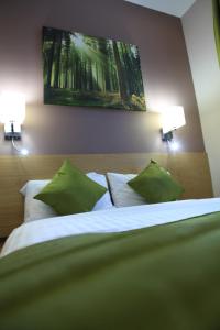 ein Schlafzimmer mit einem Bett mit zwei grünen Kissen in der Unterkunft Sheriff Hotel in London