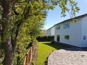 una casa blanca con una valla y un árbol en Anglesey White Haven en Llandegfan