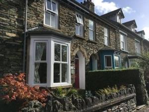 Casa de ladrillo con puerta blanca y ventanas en Ingle Burrow, en Windermere