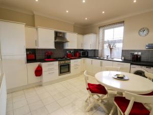 a kitchen with white cabinets and a table with chairs at Apartment 3 Marian Y Mor in Pwllheli
