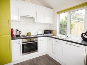 Una cocina con gabinetes blancos y una ventana. en 73-The Lodge, en Llanina 2 fotos más