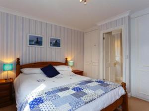 a bedroom with a bed with a blue and white quilt at Glebe House in Aveton Gifford