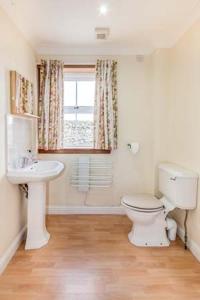 a bathroom with a toilet and a sink and a window at Little Laight in Cairnryan