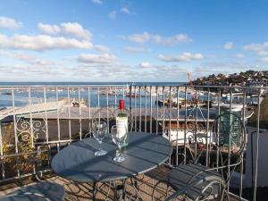 a table with a wine bottle and two glasses on a balcony at Blue Horizon in Brixham