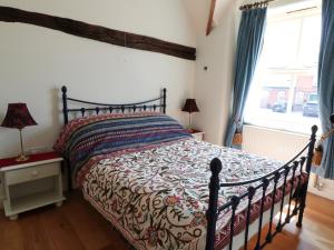 a bedroom with a bed with a comforter and a window at Just A Cottage, Newlands Farm in Swanwick