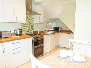 uma cozinha com armários brancos e um forno com placa de fogão em Amelia Cottage em Battle