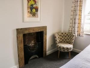 a living room with a fireplace and a chair at Olive Cottage in Richmond