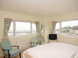 a bedroom with a bed and two chairs and windows at Blue Horizon in Brixham