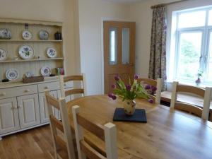 un tavolo da pranzo con un vaso di fiori sopra di Eribel Cottage a Threlkeld Altre 18 foto