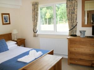 a bedroom with a bed and a dresser and a window at Whitbarrow Holiday Village Troutbeck 5 in Penruddock