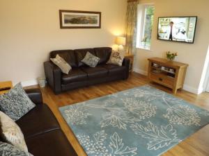 a living room with a leather couch and a blue rug at Eribel Cottage in Threlkeld