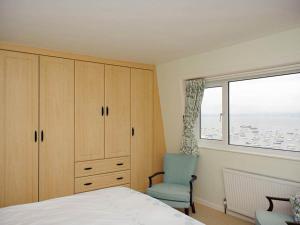 a bedroom with a bed and a chair and a window at Blue Horizon in Brixham