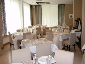 una sala da pranzo con tavoli e sedie bianchi di Hotel Touring a Carpi