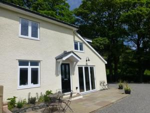 a white house with a black door and windows at Eribel Cottage in Threlkeld