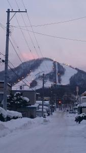 a snowy street with a ski lift in the distance at B&B HOTTA in Sapporo