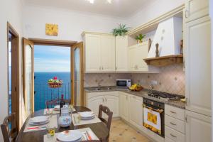 a kitchen with white cabinets and a table with a view of the ocean at Casa I Girasoli in Praiano